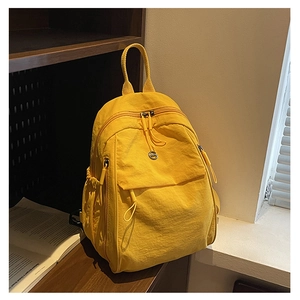 Détail du sac à dos en nylon jaune avec plusieurs poches posé sur une étagère