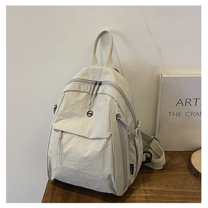 Détail de la poche latérale et de la texture en nylon du sac à dos blanc crème