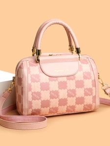 Detailed macro of pink plaid handbag showing wide woven strap and golden metal hardware