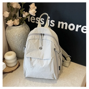 Détail d'un sac à dos en nylon gris clair avec texture froissée sur fond épuré