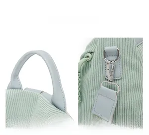 Detail view of mint corduroy bag featuring leather handle and detachable metal buckle strap