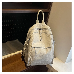 Détail d'un sac à dos minimaliste en nylon crème avec poche avant dans un décor cosy