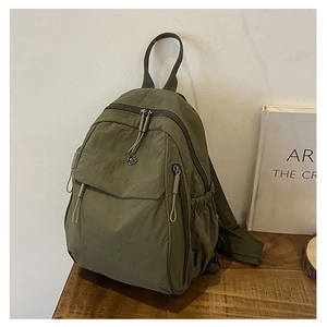Détail d'un sac à dos en nylon vert olive avec texture imperméable et emblème métal