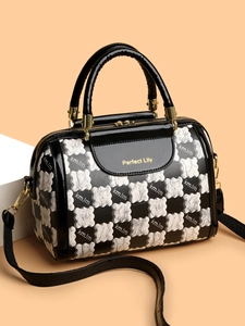 Detail of checkered Boston bag featuring gold Perfect Lily logo and black patent handles