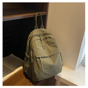 Détail d'un sac à dos en nylon vert clair sur une étagère, focus sur texture et logo