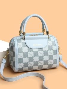Detail of light blue PU leather handbag with clover patterns and golden metal hardware