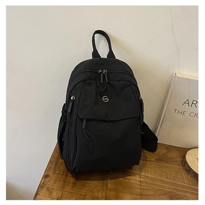 Détail d'un sac à dos noir minimaliste avec poche avant et poignée supérieure durable