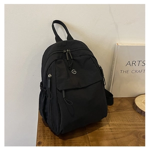 Détail d'un sac à dos en nylon noir avec logo circulaire sur table en bois
