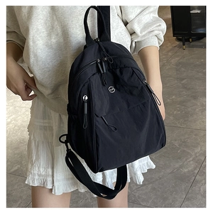 Détail d'un sac à dos en nylon noir avec fermetures éclair et écusson circulaire