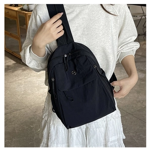 Détail d'un sac bandoulière en nylon noir léger avec fermeture tissée et logo métallique