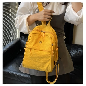 Détail d'un sac à dos en nylon jaune avec poches zippées fonctionnelles et logo en métal