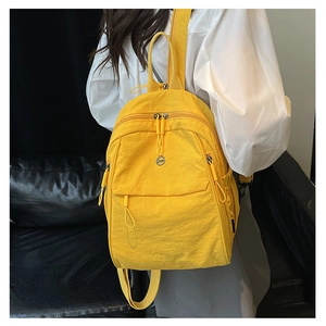 Sac à dos en nylon jaune avec poche zippée et cordon décoratif porté par un mannequin