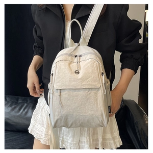Détail d'un sac à dos blanc crème minimaliste avec texture nylon et étiquette logo