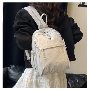 Détail d'un sac à dos en nylon blanc crème minimaliste porté avec plusieurs compartiments