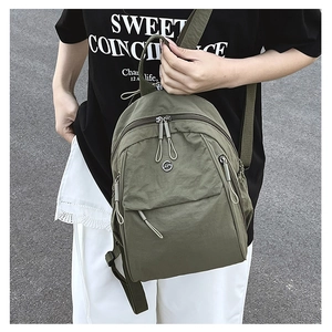 Détail du sac à dos en nylon vert armée avec poche zippée et plaque logo en métal
