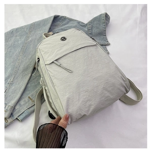 Gros plan du sac à dos en nylon gris clair avec logo rond et détails de veste en jean