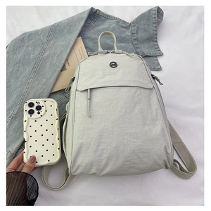 Détail de la texture en nylon d'un sac à dos gris clair polyvalent avec poignée tissée