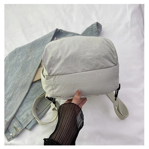 Détail d'un sac bandoulière en nylon gris clair avec sangle tissée sur veste