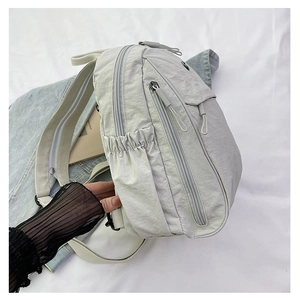 Vue détaillée d'un sac à dos en nylon gris clair avec compartiments et zips métalliques
