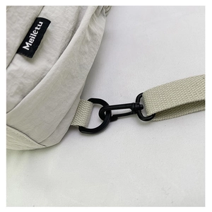 Détail de l'anneau en D noir mat et étiquette sur le sac en nylon gris clair