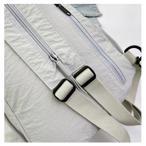 Détail d'un sac à dos en nylon gris clair avec double fermeture éclair et bretelles