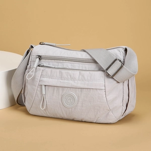 Light grey multi-compartment nylon crossbody bag with adjustable wide strap and round logo