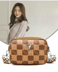 Détail du sac bandoulière à damier avec boucle argentée en V et large bandoulière
