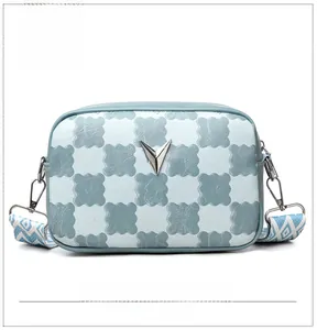 Détail du sac bandoulière à damier bleu avec texture ondulée et boucle métallique en V
