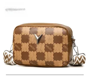 Détail du sac photo bandoulière avec gaufrage en damier, boucle en V et bandoulière