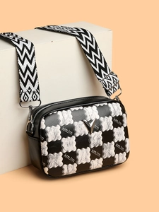 Détail du sac à carreaux avec logo en V et bandoulière ondulée sur fond orange chaud