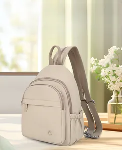 Detail view of beige nylon backpack with multiple zipper compartments and side pockets