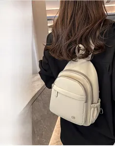 Detailed view of cream PU mini backpack with multi-zipper layers on a model in sunlight