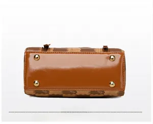 Close-up of brown glossy leather handbag bottom with four protective gold metal studs