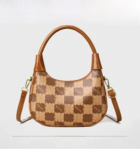 Detail of color-block handbag showing brown monogram pattern and golden hardware
