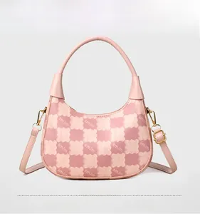 Detail view of pink and white checkered leather handbag with golden metal hardware