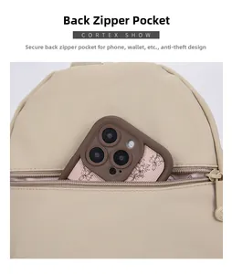 Detail view of the secure back zipper pocket on a beige backpack with floral phone accessory