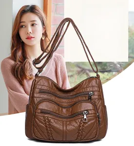 Detailed view of brown PU leather shoulder bag featuring three tiered zipper front pockets