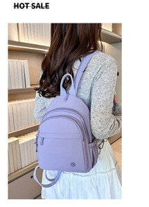 Detail of purple nylon backpack with multiple compartments shown on model in library
