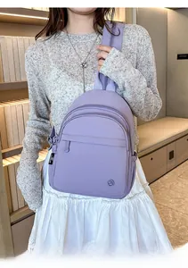 Detail of lilac nylon backpack with multiple zipper pockets worn in a cozy lifestyle setting