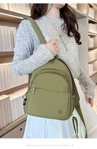 Detailed side view of green nylon backpack with multi-layered zipper compartments and side pocket