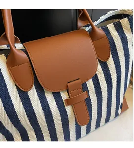 Detail of navy stripe tote bag with brown litchi leather flap and metal buckle