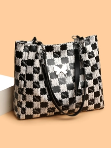 Détail de l'emblème papillon argenté sur un sac fourre-tout à damier avec lanières en cuir