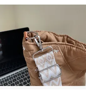 Gros plan du sac fourre-tout matelassé caramel avec nœud brodé et bandoulière en jacquard