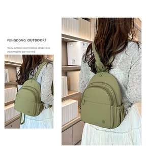 Detail view of avocado green lightweight nylon mini backpack with multiple zipper pockets