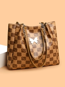 Détail d'un cabas marron avec texture quadrillée et ornement papillon en métal argenté