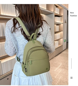 Olive green mini backpack shown on model with adjustable straps and multi-pocket detail