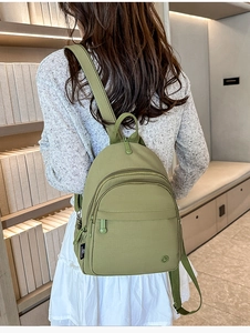 Matcha green mini nylon backpack shown on model in a cozy library setting