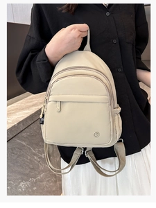 Detail of cream mini backpack with dual zippers and adjustable brown straps