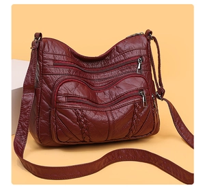 Detail of burgundy PU leather crossbody bag with multiple zippers and woven side texture