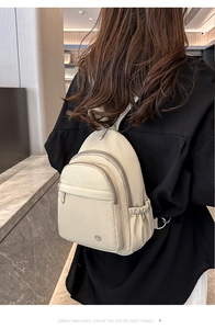 Detail of light beige water-resistant nylon backpack with multiple zippered compartments